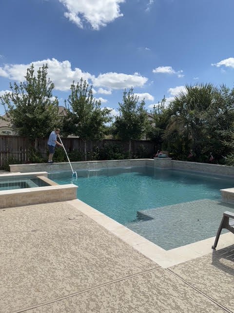 Pro Pool Houston skimming a backyard pool with a leaf net